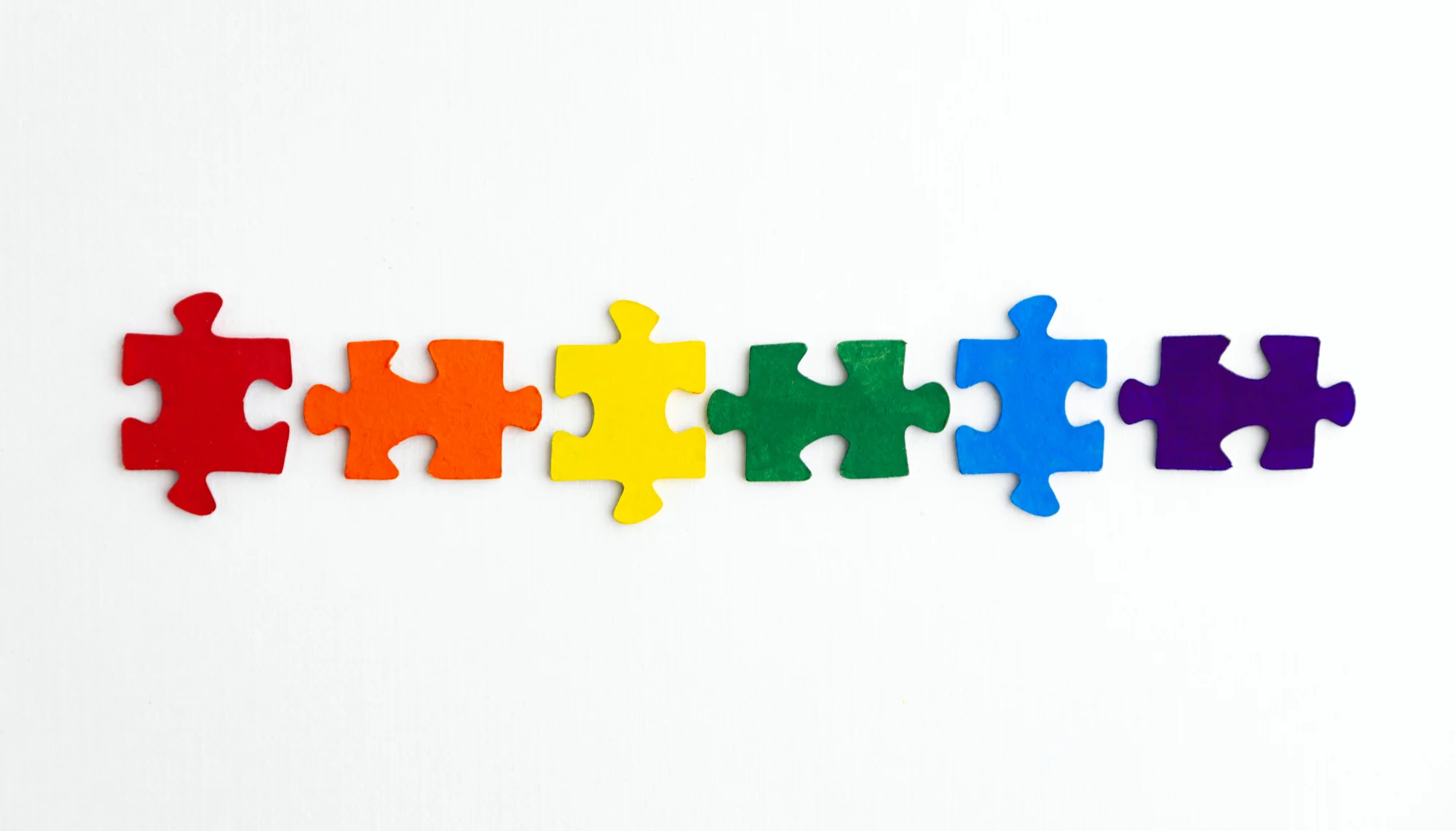 Filz-Puzzlesteine in Regenbogenfarben in einer Reihe angeordnet