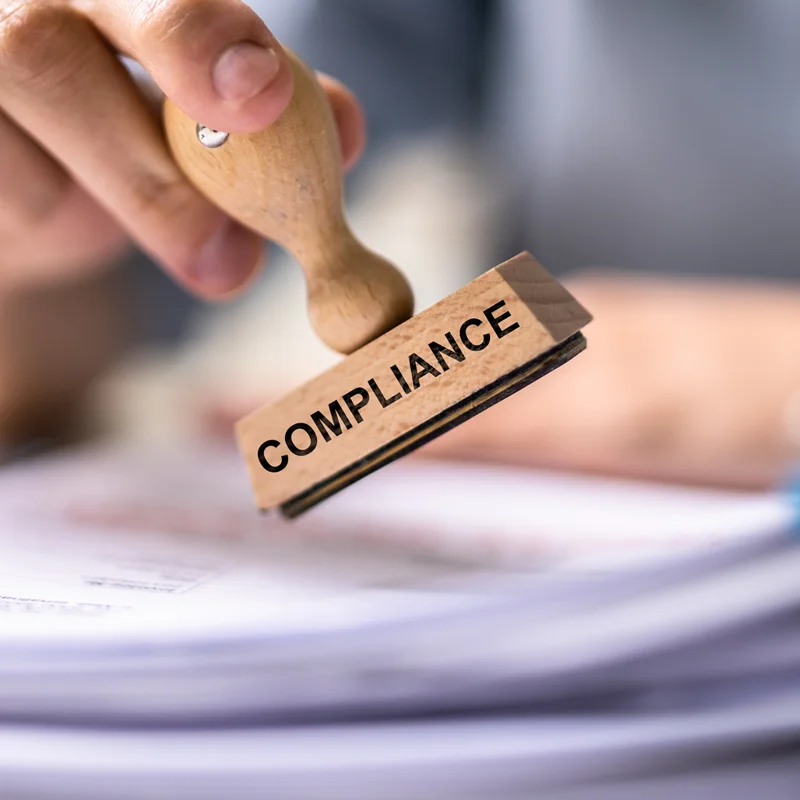 Eine Hand hält einen Stempel mit der Aufschrift Compliance