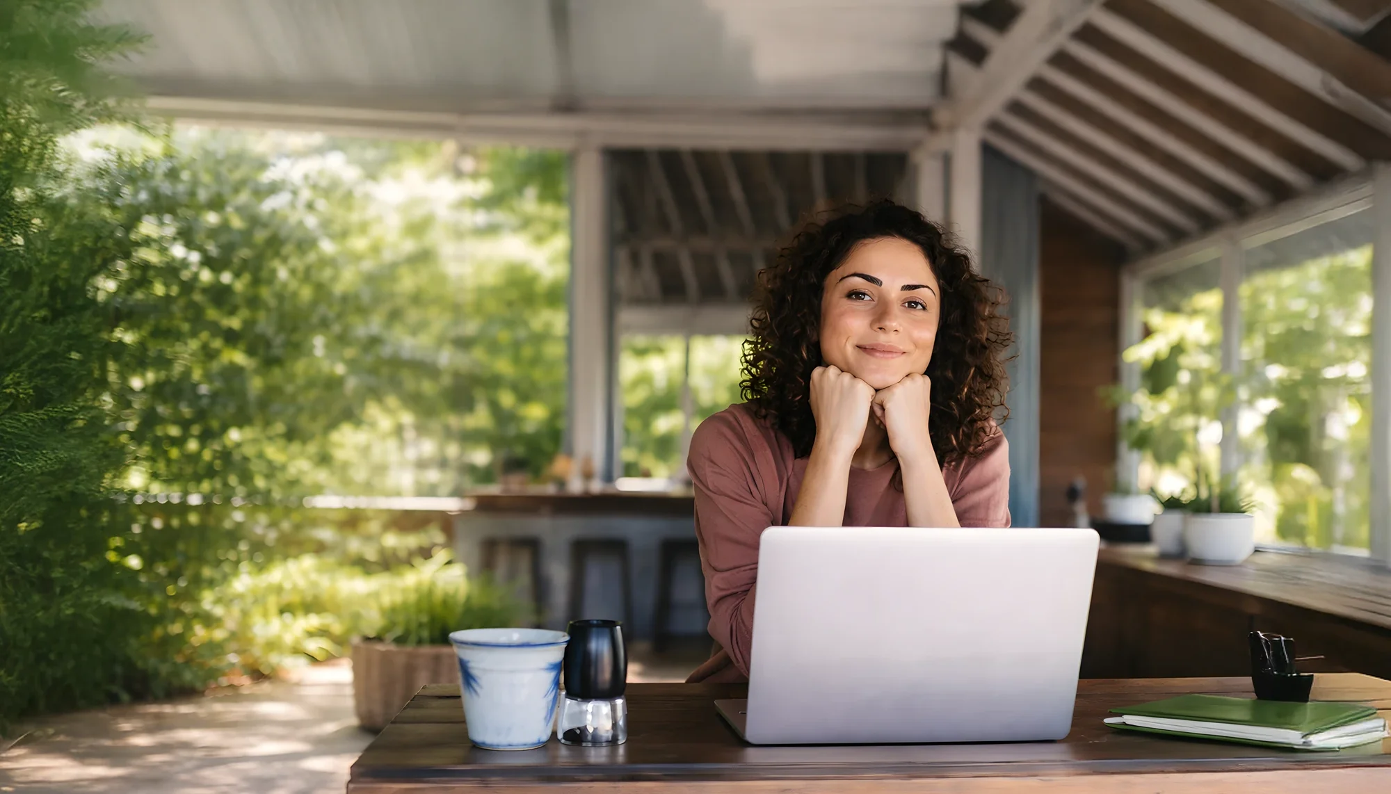 Junge Frau sitzt auf ihrer Terrasse vorm Laptop