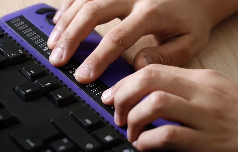 Person tippt auf Braille-Tastatur