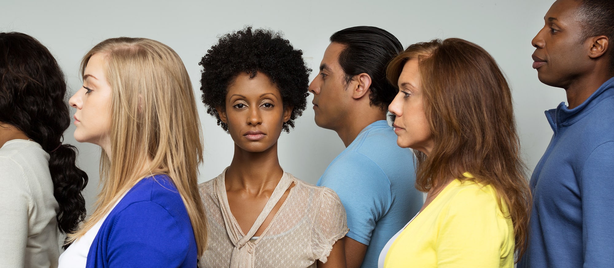 Frau mit dunkler Hautfarbe steht allein in einer Gruppe